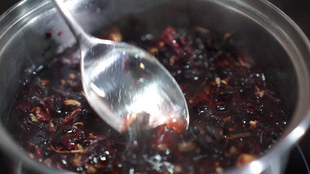 Red tea Hibiscus sabdariffa rose petals herbal infusion boiled in silver pot spoon stir
