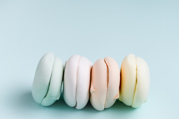 Colored sweet dessert zephyr marshmallows . Air colrful zephyr on blue background, pastel colors. Close up, food photography