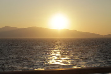 The fiery sun slowly falls over the horizon, the water plays with golden rays and the island is...