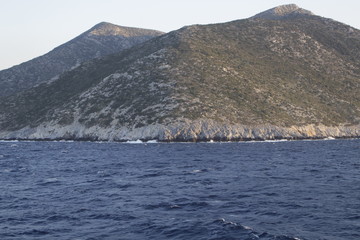 The waves beat against the impregnable shore of the island towering above the sea, the hills stretch into the sky lit by the rays of the sunset.