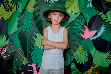 A child in a traveler hat on a background of leaves. Child traveler