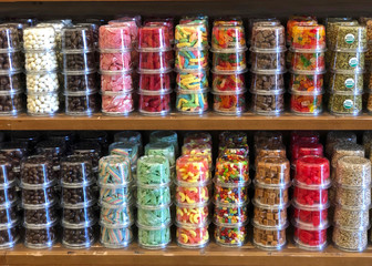 Shelf with rows of chocolate covered nuts and various candies stacked for sale. Individually packaged to ensure safety from contamination.