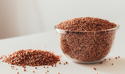buckwheat in a glass bowl on a white table on a white background. copyspace