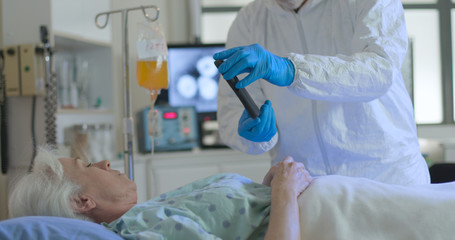 A healthcare professional helps a patient who is hospitalized with COVID19 coronavirus keep in...