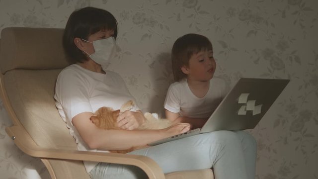 Mother, toddler son and cat sit together on chair with laptop. Woman tries to remote work, but kid is asking for game or cartoons. quarantine lockdown because of coronavirus COVID-19. 10bit V-logL