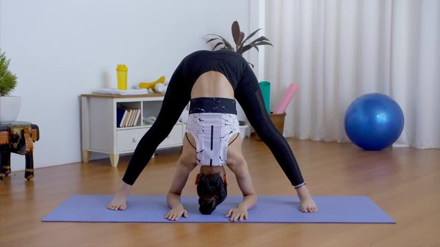 Closeup shot of young flexible girl practicing yoga postures on a fitness mat - health at home. Healthy Indian female performing the types of bending poses like Prasarita Padottanasana and Janu Sir...
