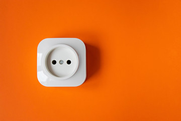 White electrical power socket on orange background - obrazy, fototapety, plakaty