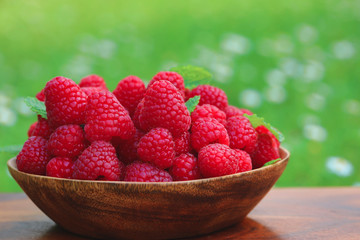 Ripe raspberries on bowl with nature background. Healthy eating concept