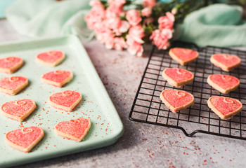 Close up of Valentine's day heart cookies cooling on a pan and rack.