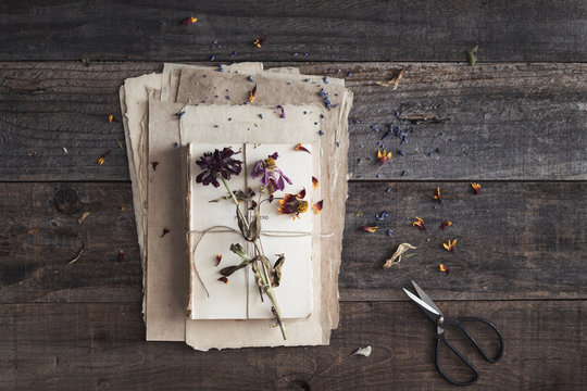 paper and book layers with scattered dried flowers, petals and scissor
