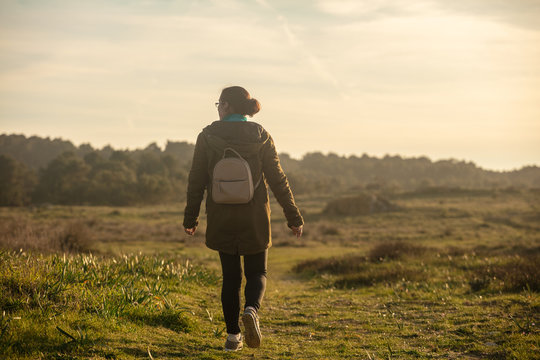 Woman with a small backpack walking through a natural grassland