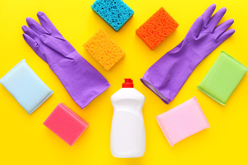 Colorful cleaning set for different surfaces in kitchen on yellow background. Top view, flat lay