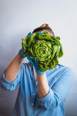 Young woman holds a fresh salad in her hands. Blue background, isolated. Delivery.