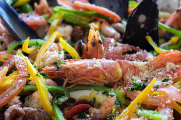 Close up photo of  shrimp, seafood paella inside pot pan.