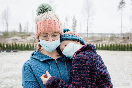 mother carrying son with face masks on for protection from virus & flu