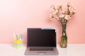 Laptop mock up on white table with a beautiful pink carnation flowers