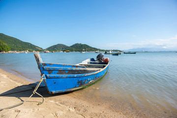 Fototapeta premium Front view of fishing boat on the beach with blue sky background in Florianopolis,