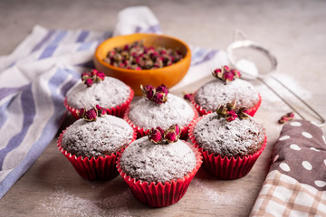 Chocolate muffins with powdered sugar and decor of dried tea roses.