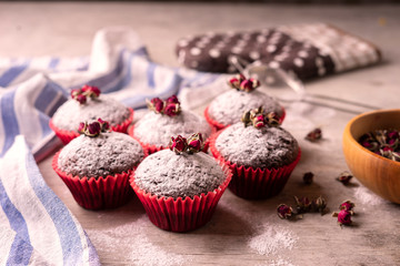 Chocolate muffins with powdered sugar and decor of dried tea roses.