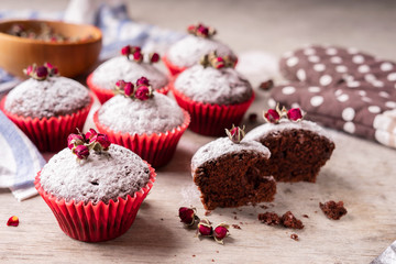 Chocolate muffins with powdered sugar and decor of dried tea roses.