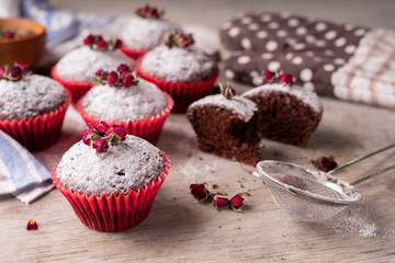 Chocolate muffins with powdered sugar and decor of dried tea roses.