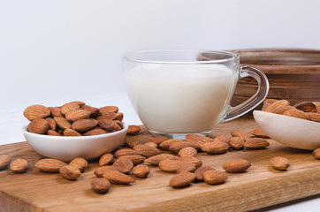 Almond milk in cup with nuts on white background