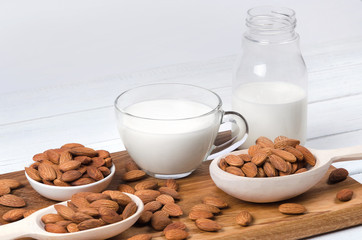 Almond milk in cup and bottle with nuts on white background