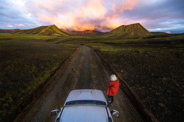 Photographer taking picture of sunset on mountains next to car