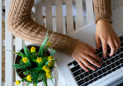 Hands typing on a white laptop.