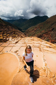 Young woman is walking near the famous salt mines in Peru