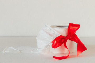 white toilet paper with a red bow on a white background. White medical mask