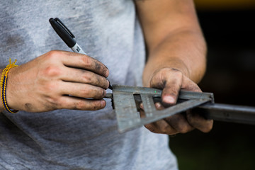 Construction worker using speed square to measure angle on steel.