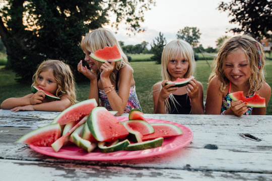 Siblings having fun eating watermelon outside in summertime