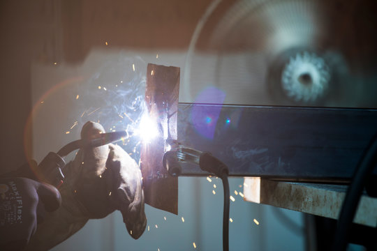 Detailed side view of welder working in shop.