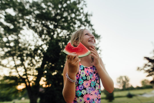 Young girl with big smile eating watermelon during the summer outside