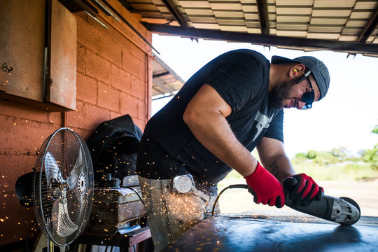 Worker concentrating, using angle grinder to cut steel.