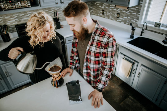 man and woman couple stand together in kitchen making coffee