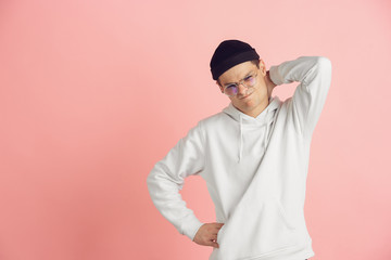 Dissatisfied with something. Caucasian young man's modern portrait isolated on pink studio background. Beautiful male model in white. Concept of human emotions, facial expression, sales, ad. Copyspace