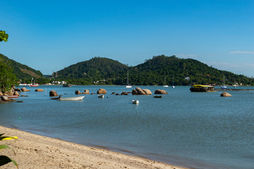 Fototapeta na wymiar Beautiful beach landscape in Brazil. Calm turquoise sea with fishing boats and sailboats moored near the shore. Photo with space for text. Concept of tourism and beach holidays.
