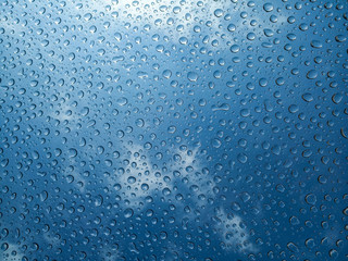 Drops of water on the glass. Sunny daytime blue sky. Transparent dew drops after rain. Bright photo...