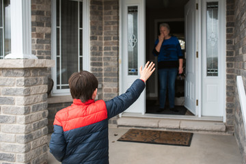 Social distance visit between young boy and his grandmother at home.