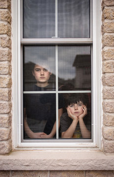 Portrait of siblings looking through window