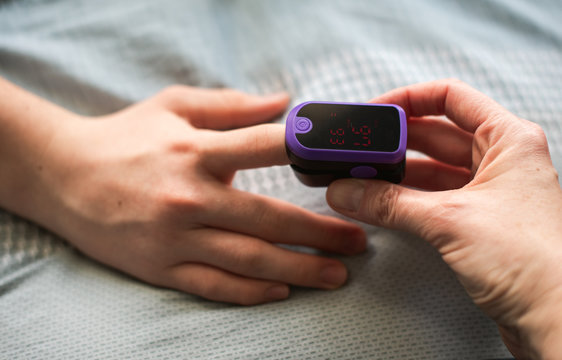 Close up of a hand putting a pulse oximeter on someone's finger.