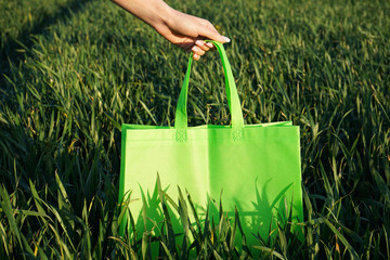 Eco-bag. Woman holding an eco bag outdoors. Layout for design. Field of wheat.
