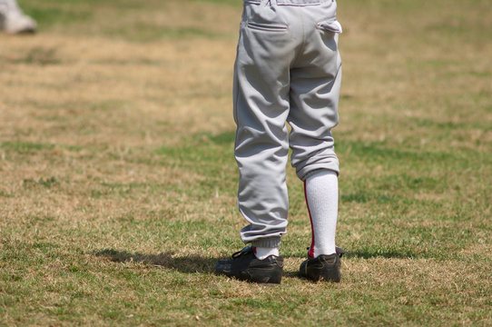 boys legs wearing uneven baseball pants