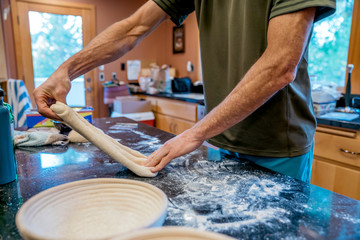 Man stretching sourdough bread dough in messy kitchen