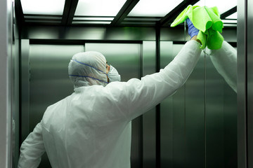 coronavirus. Worker disinfecting hospital elevator to avoid contagion.