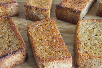 Pieces of fried croutons laid out in a row on a wooden Board close up and copy space top view