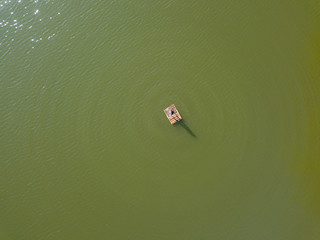A fisherman on a raft in the middle of a lake. Aerial drone view.