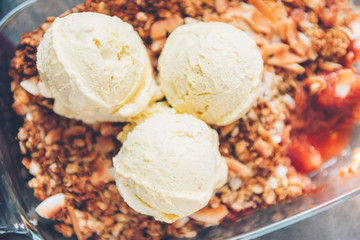 Home cooked Rhubarb and Strawberry crumble from oatmeal and nuts topping and with vanilla ice cream scoops